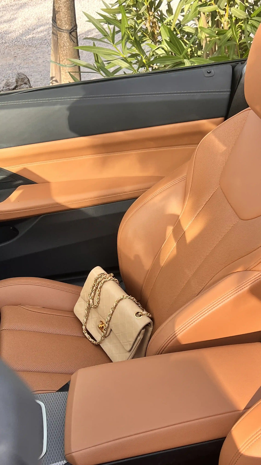 beige chanel small classic flap on a brown leather car seat