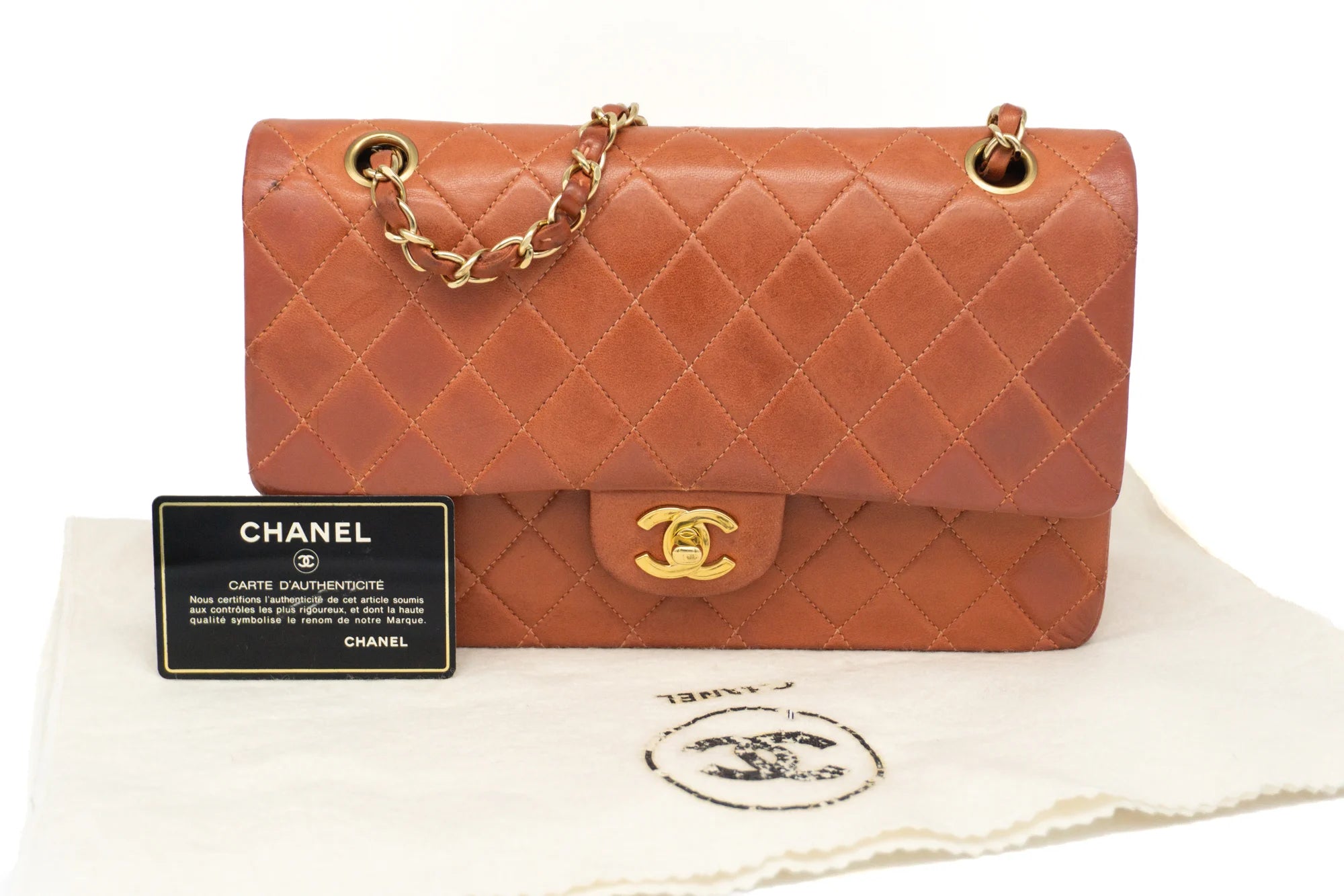 Chanel Medium Classic Flap in rust red front view with authenticity card and dustbag