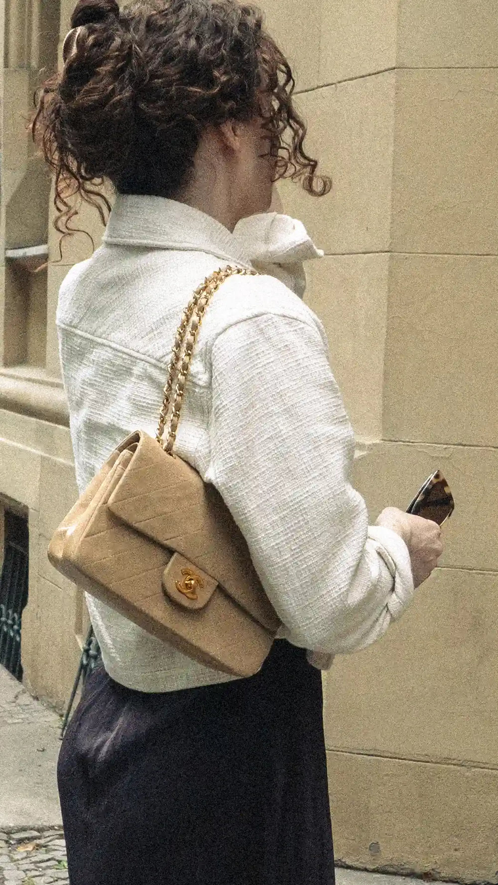 woman wearing a beige chanel small classic flap over her shoulder